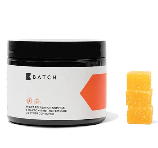 A jar of BATCH THC Tangerine Uplift gummies sits next to a three gummy stack. These gummies from BATCH are one of our best products for Memorial Day Weekend.